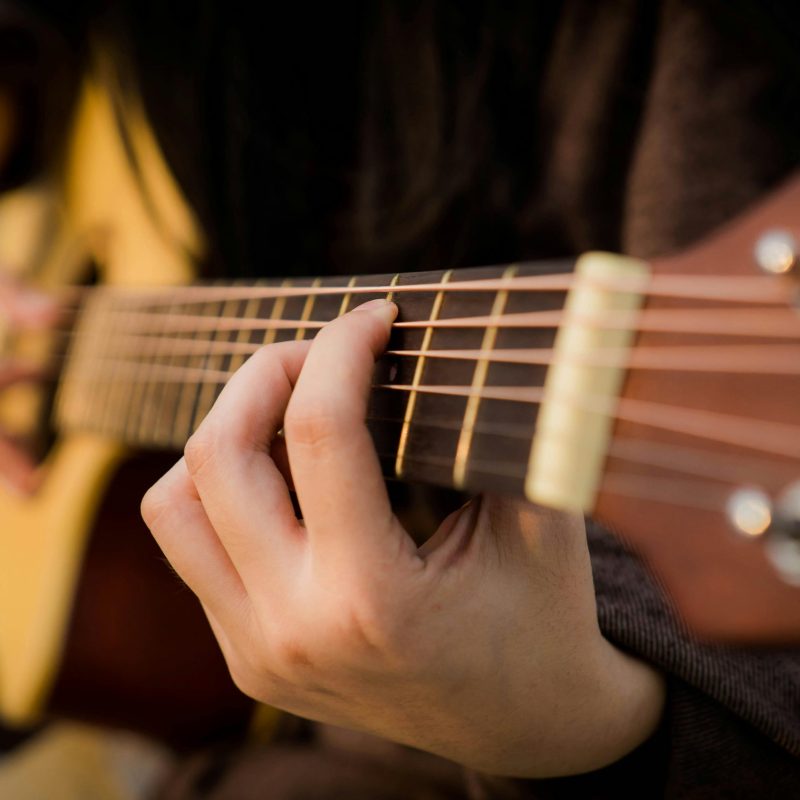 pexels-photo-2118045-2118045 Close view of fingers strumming an acoustic guitar, capturing the essence of music creation.
